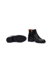 Bottines en cuir noir avec un bout rond, fermeture à glissière et semelle en caoutchouc texturée. Elles présentent un petit talon empilé et un design minimaliste.