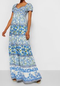 Maxi šaty z lehké látky s květinovým vzorem. Modré a zelené barvy s nabranými balónovými rukávy a detailem zřaseného korzetu.