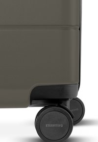 Hartschalenkoffer in Olivgrün mit strukturiertem Finish, ausgestattet mit Gummirädern und dem Markennamen "ETERNITIV3" auf der Radverkleidung.