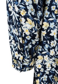 Blumenbluse mit navy Hintergrund und weißen sowie gelben Blumen, gerafften Ärmeln und knöpfbaren Manschetten aus weichem Stoff.