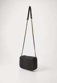 Borsa a tracolla in pelle trapuntata nera con catena, caratterizzata da una parte superiore arrotondata e un motivo di cucitura verticale, insieme a dettagli in hardware dorato.
