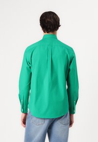 Camicia a maniche lunghe di un vivace verde, realizzata in cotone leggero, con colletto classico e polsini con bottone, e una piega sul retro.