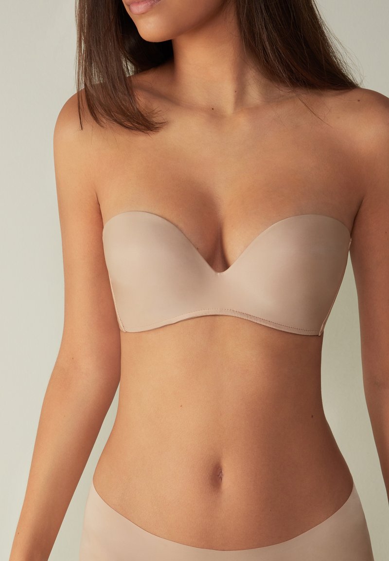 Beige strapless bh van gladde stof met een gevormde cupontwerp. Het materiaal heeft een matte afwerking en biedt naadloze dekking.