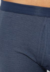Marinblå randiga boxershorts med en enfärgad mörk midja. Tyget har en fin, ribbad struktur och horisontella vita ränder.