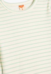 Lysegrøn og hvid stribet babyt-shirt i ribbet tekstur med rund hals. Har et orange vaskeetiket ved halsudskæringen.