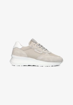 Lichtgrijze sport schoen gemaakt van suede en stoffen materialen. Bevat witte accenten, gestructureerde zolen en contrasterende zwarte veters. Merklogo zichtbaar.