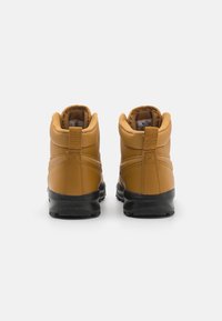 Botas de cuero marrón, tipo tobillo, con un acabado texturizado, suelas de goma negras y cuellos acolchados. Marcadas con una etiqueta de la marca en el tacón.