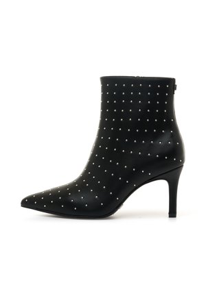Stivale alla caviglia in pelle nera con punta affusolata, caratterizzato da borchie argentate disposte in un motivo. Il tacco a stiletto misura circa sette centimetri.