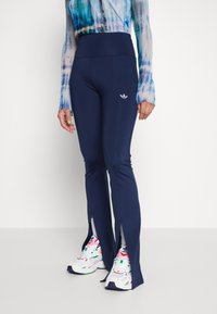 Marina atletiska leggings med hög midja, med sidofickor vid anklarna. Kombinerade med färgglada sportskor.