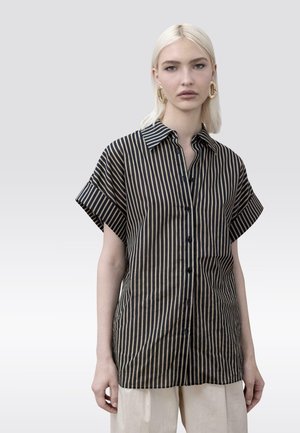 Camisa de manga corta a rayas en negro y beige, con cierre abotonado en la parte delantera, cuello puntiagudo y ajuste relajado. Tejido suave y liso.