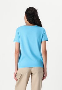 T-shirt in cotone azzurro chiaro con scollo tondo e maniche corte, caratterizzato da una vestibilità comoda e una superficie liscia, abbinato a pantaloni beige.