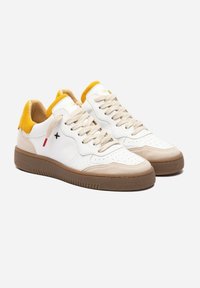 Sneaker bianche in pelle con dettagli gialli e beige. Punta traforata e suola in gomma beige con texture rigata.