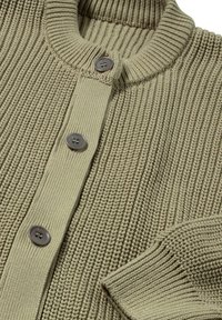 Stickad kofta i ljus olivgrön med ribbad struktur, med rund halsringning och tre grå knappar framtill.
