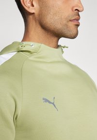 Lichtgroene hoodie van zachte stof met een trekkoordkap, witte accenten en een grijze Puma-logo op de borst. Glad textuur.
