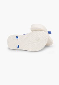Weißes Flip-Flop mit einem blauen Riemen. Die strukturierte Sohle verfügt über ein Diamantmuster und zwei runde Akzente in Blau. Leichtes Design für den Freizeitgebrauch.