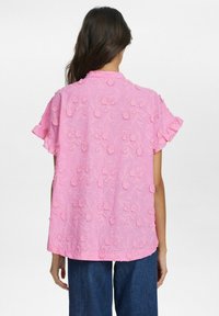 Blusa rosa ricamata con motivo floreale, maniche corte a balze e taglio dritto. Tessuto morbido e leggero.