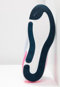 Podešev bílo-námořnicko-modrých sportovních bot s růžovými akcenty, ukazující detailní vzor podešve a branding "AIR MAX".