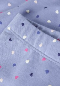 Jasnofioletowy materiał z małymi wzorami serc w kolorze białym, różowym i ciemnofioletowym, z widocznymi złożonymi szwami.