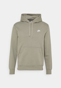 Olivgrön Nike-hoodie med framficka i kängurustil, snörhals och vit Nike-logotyp på vänster bröst.