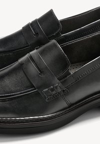 Zwarte leren instappers met een gladde afwerking, voorzien van een gestikt ontwerp, riemdetail en een rubberachtige zool voor extra comfort.