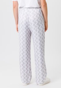 Lightweight, high-waisted trousers in a white and grey circular pattern, featuring a smooth texture and straight-leg design, worn with a t-shirt.