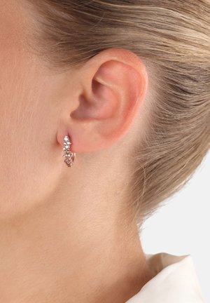 Orecchini a cerchio in oro rosa con un delicato disegno di piccole pietre scintillanti lungo il bordo frontale, che mostrano un design testurizzato.