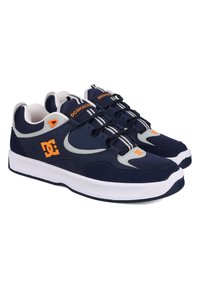 Navy blue sneakers with gray accents, featuring a mesh and suede upper, white rubber sole, elastic laces, and a prominent orange logo.