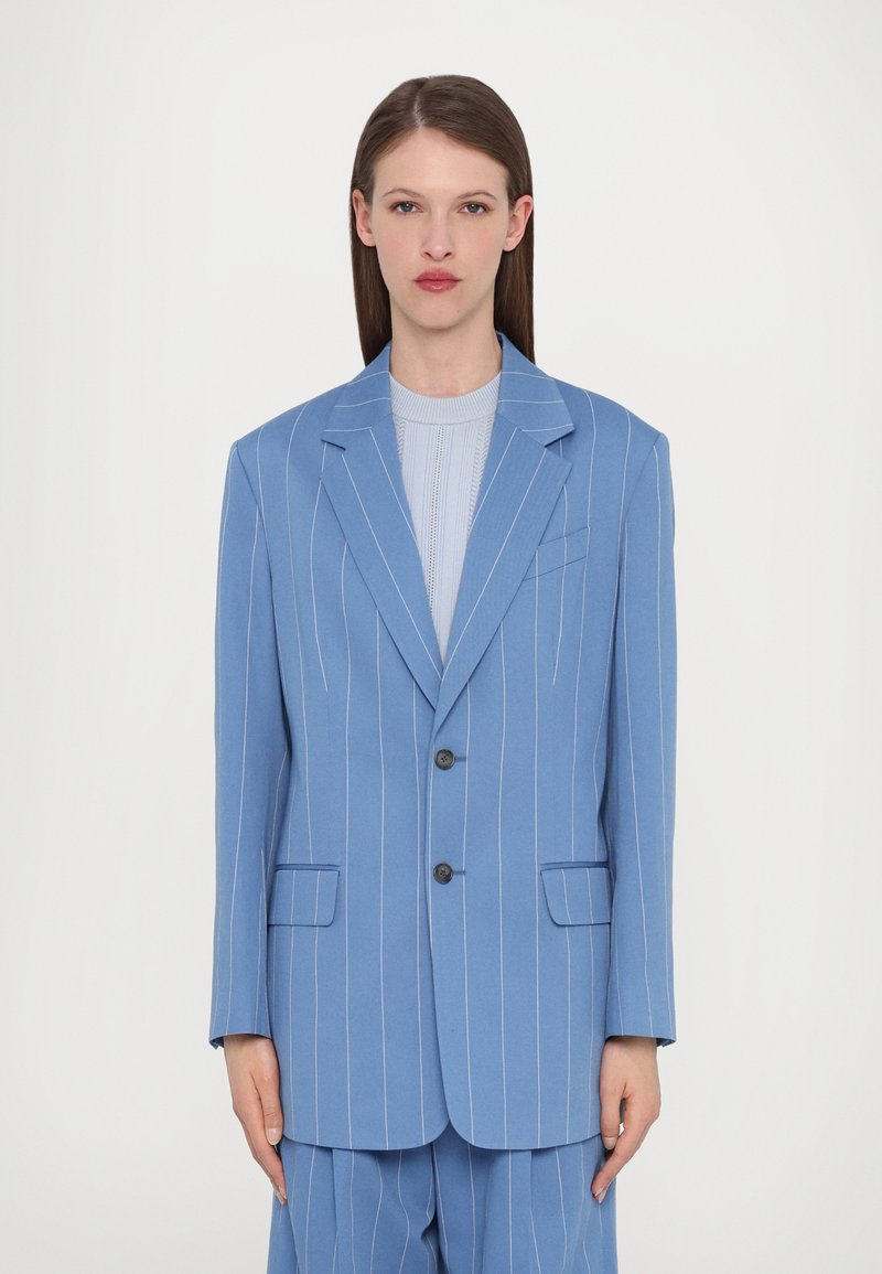 Light blue pinstripe blazer with two buttons, notch lapels, and two front pockets, made from a smooth fabric with a structured fit.