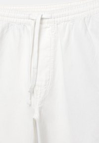 Vita bomullsshorts med elastisk midja och dragsko. Funktioner inkluderar vertikal sömnad och en sidoficka. Slät textur.