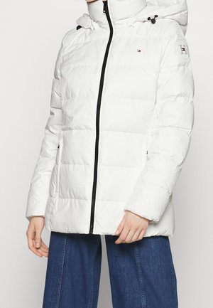 Chaqueta acolchada blanca con cierre de cremallera, que cuenta con una capucha y cordones elásticos. Fabricada con un material suave y acolchado, con bolsillos laterales.