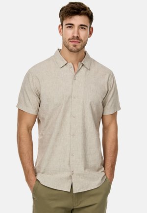 Camisa de manga corta abotonada en tejido beige claro con una textura sutil. Presenta un cuello con puntas hacia adelante y botones de color claro.