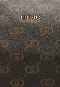 Tumepruun tekstureeritud nahk korduva heledama pruuni põimunud "LJ" logo mustriga ja keskele asetatud kuldse "LIU·JO" brändinimega.