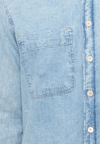 Hellblaues Jeanshemd mit aufgesetzter Tasche, Knopfverschluss und feiner Textur mit sichtbaren Nahtdetails.
