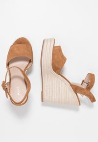 Sandales compensées en daim marron avec brides chevilles et semelles plateforme en corde tressée, vues de dessus et de côté sur fond blanc.