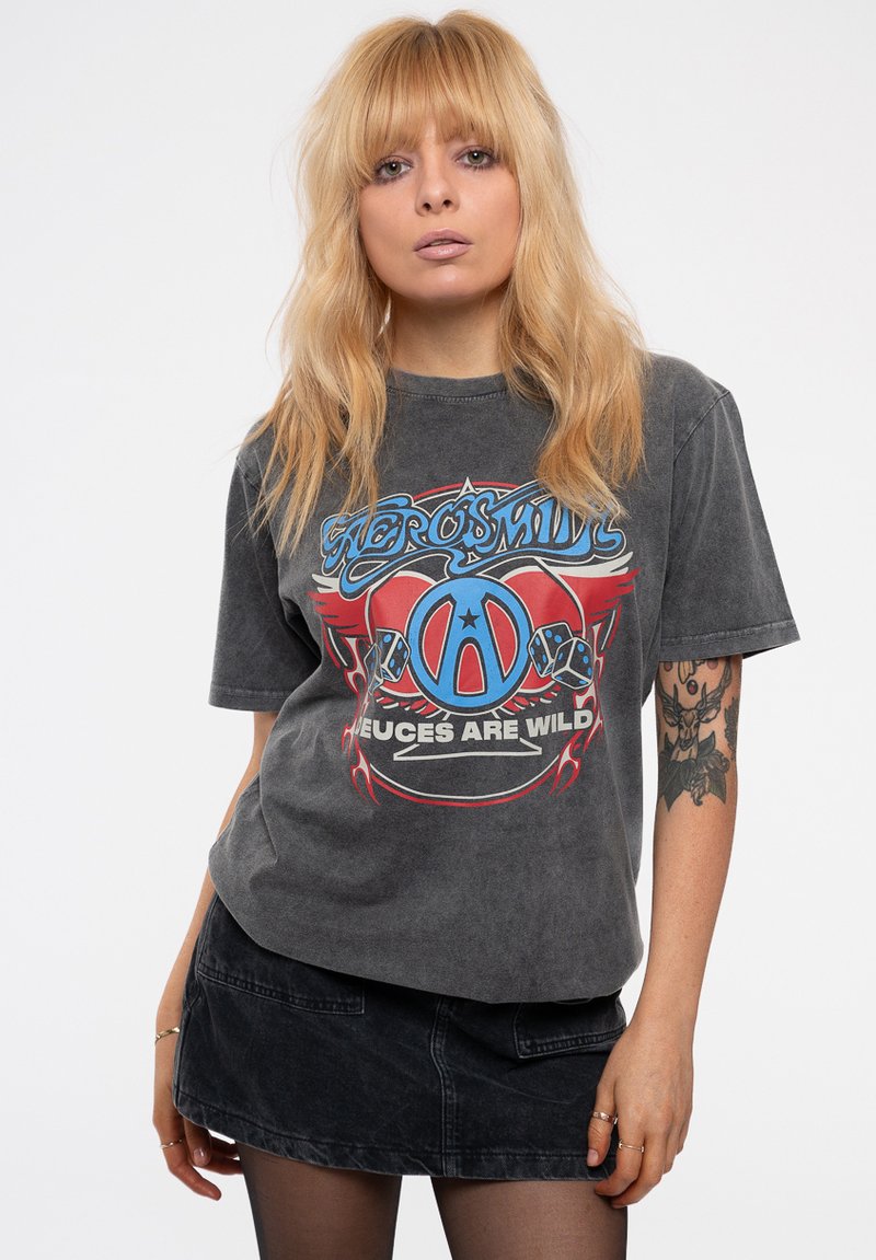 Gray graphic t-shirt featuring a blue and red design with text. Short sleeves and a relaxed fit. Worn with a dark denim skirt.