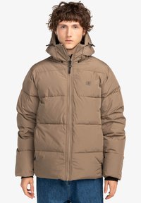 Giacca puffer beige con colletto alto, zip frontale e cordini sul cappuccio. Presenta sezioni trapuntate e un logo discreto sul petto.