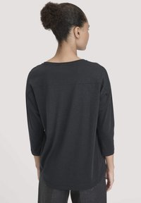 Schwarzes Shirt mit drei Viertelärmeln, aus weichem Stoff gefertigt, verfügt über einen runden Ausschnitt und eine entspannte Passform, mit einer Nahtdetails über dem oberen Rücken.