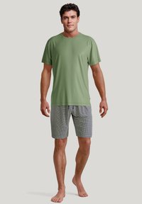 Green short-sleeve shirt paired with patterned gray shorts featuring a geometric design. Both items are relaxed fit and lightweight.