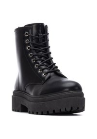 Botas de cuero negras hasta el tobillo con punta redondeada, suela de plataforma gruesa, ojales de metal y cordones. Textura suave y diseño robusto.