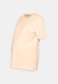 T-shirt de maternidade em pêssego claro, feito de algodão suave, com um corte descontraído, mangas curtas e um detalhe de texto sutil perto da gola.