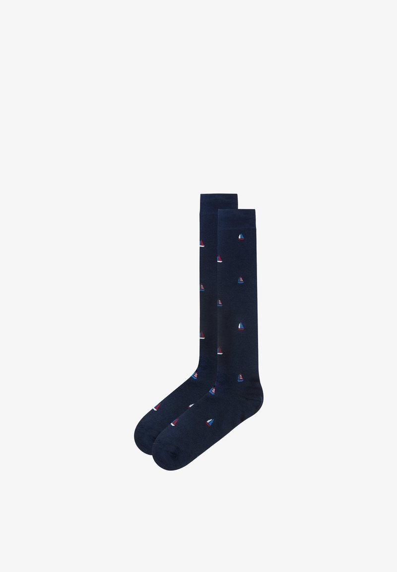 Paire de chaussettes bleu marine montant jusqu'aux genoux, ornées de petits motifs de voiliers rouges, blancs et bleus, répartis uniformément sur le tissu.