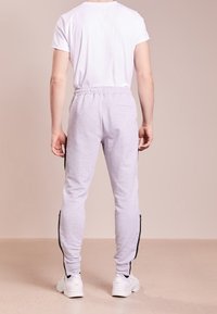 Grå sweatpants med sidslidsar, elastisk midjeband och tapered benformat, bärs med en enkel vit T-shirt och vita sneakers.