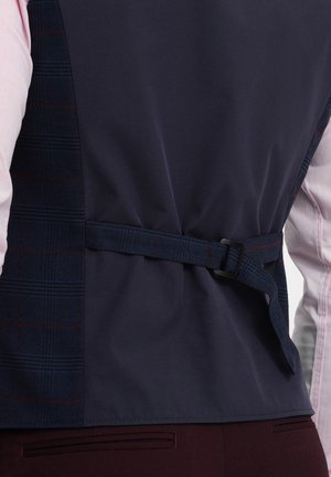 Gilet bleu marine avec un motif à carreaux sur le côté, doté d'une ceinture et d'une boucle. Tissu lisse avec une texture et des couleurs contrastées.