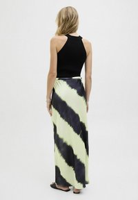 Zwarte geribbelde tanktop gecombineerd met een lange tie-dye rok in geel en zwart, met een gladde textuur en een aansluitende taille.