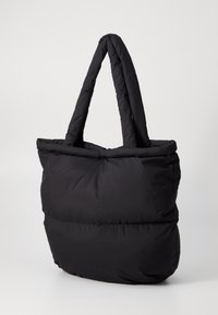 Czarna, puchata torba tote z dwiema grubymi uchwytami, charakteryzująca się miękką, pikowaną fakturą oraz przestronnym, zaokrąglonym kształtem.