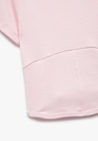 Lys pink ribbet stof med en subtil tekstur. Har en afrundet kant og korte ærmer. Rent design uden synlige logoer eller mønstre.