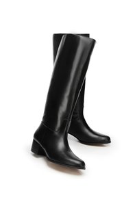 Czarne skórzane kozaki sięgające do kolan o eleganckim designie, spiczastym nosku i masywnym obcasie. Gładka faktura z minimalnymi przeszyciami.