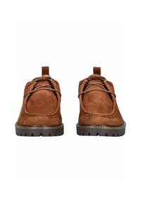 Zapatos de ante marrón con punta redondeada, detalles de cordones y suela de goma texturizada. Presentan un pequeño tacón y una pestaña en la parte trasera para facilitar el calzado.