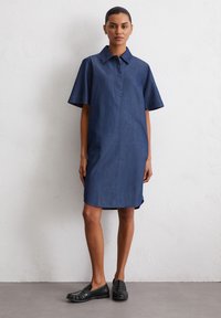 Denim shirt jurk, korte mouwen, gekraagd, donkerblauwe kleur, knie-lang, rechte snit, met een verborgen knoopsluiting en zijsplitten.