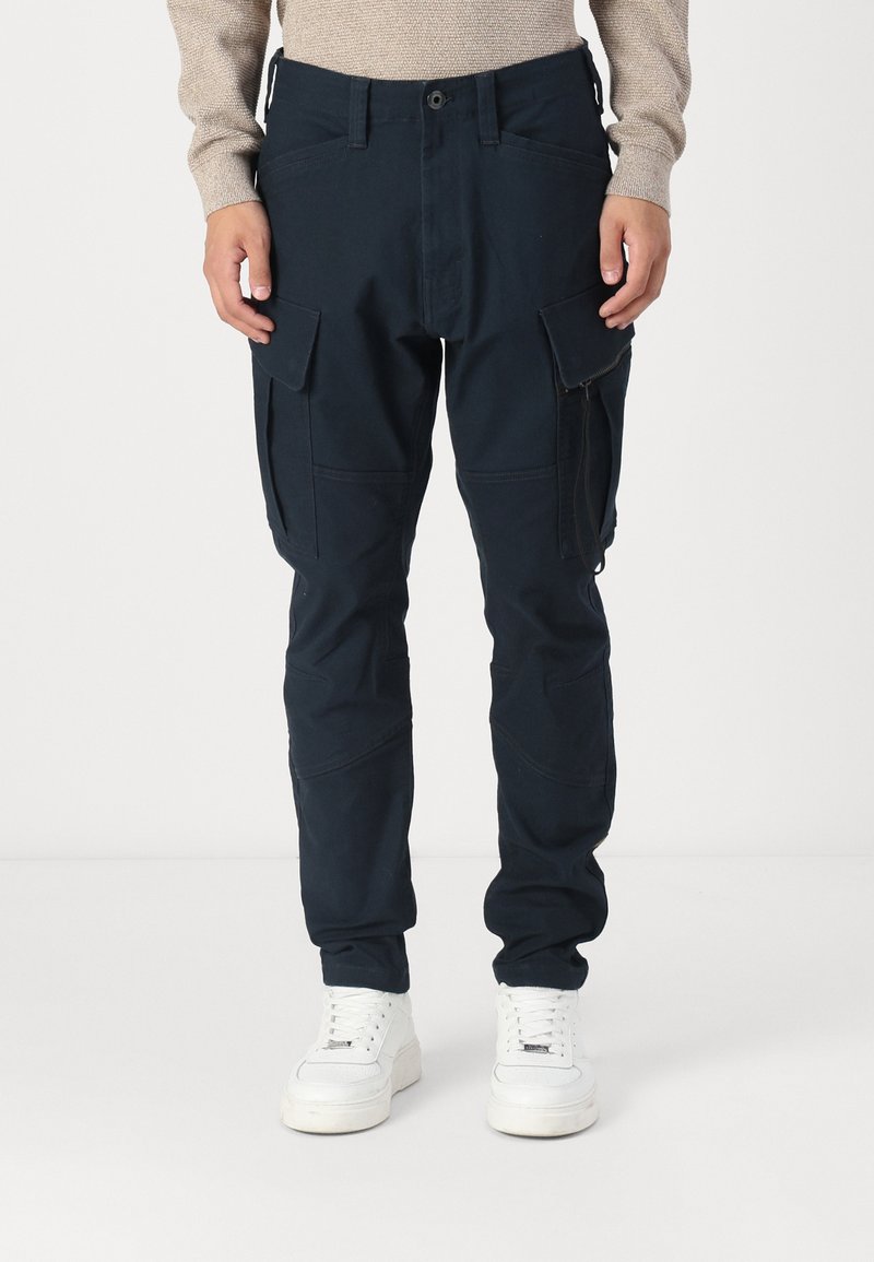 Pantaloni cargo navy dintr-un material durabil, cu multiple buzunare și o croială lejeră. Stilizați cu o închidere cu buton și detalii de cusătură minime.